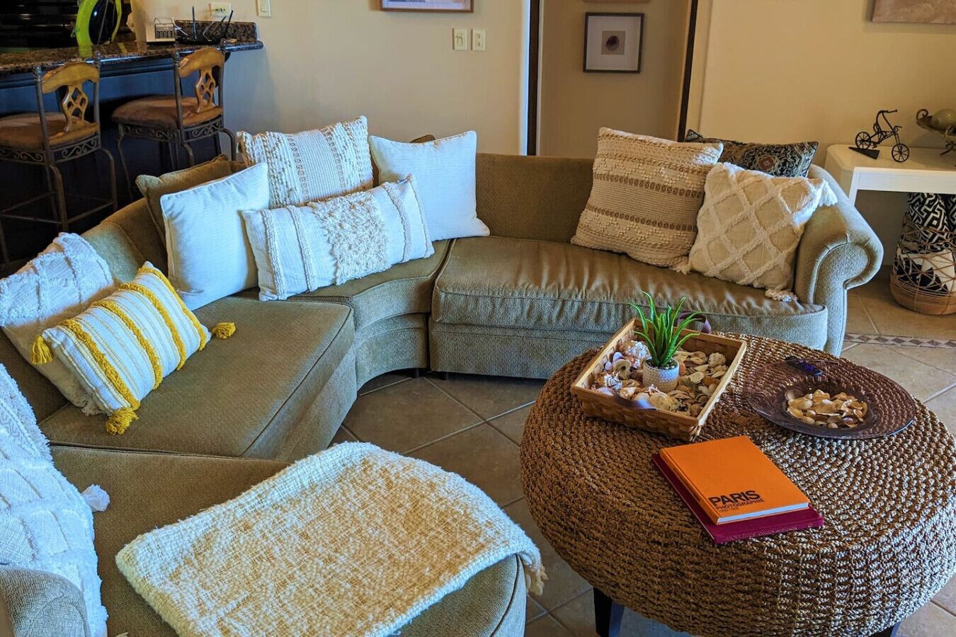 A cozy living room with a sectional sofa, a small coffee table, and a bookshelf.