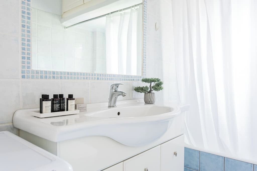 A modern bathroom with a white sink, a mirror, and a small potted plant.