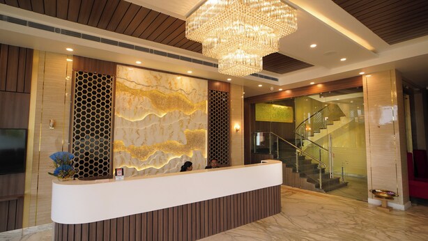 A reception area with a modern design, featuring a wooden reception desk, a large chandelier, and a marble floor. - Shanti seaview resort and spa (Kanthi)