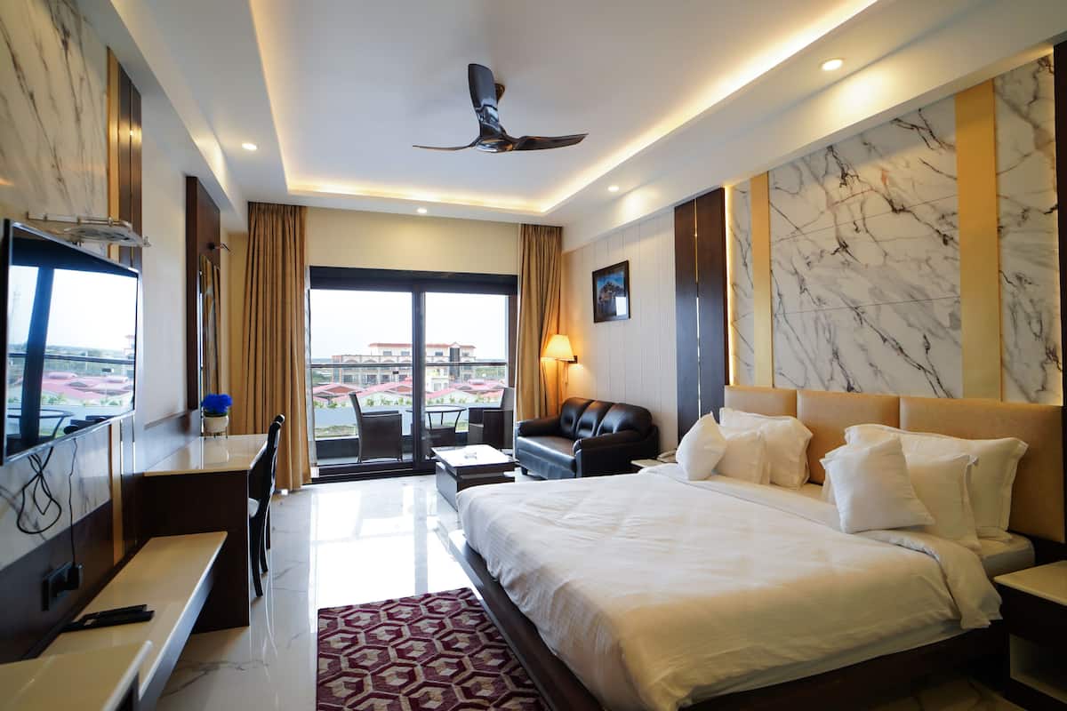 A hotel room with a bed, desk, chair, and a view of the city.