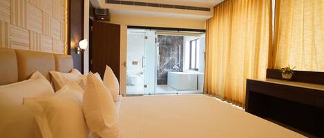 Camera d'albergo moderna con un letto grande, una televisione e vista sul bagno e sul balcone.