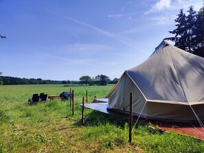 A tent set up in a grassy field with a clear sky.