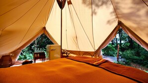 A tent with a bed, a small table, and a refrigerator. - Under Canvas Bornholm (Østermarie)
