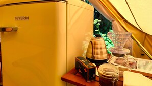 A yellow vintage refrigerator labeled 'SEVERIN' inside a tent, with a coffee maker, a glass jar, and a box on the table. - Under Canvas Bornholm (Østermarie)