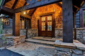 A log cabin with a stone foundation, wooden exterior, and a wooden door with glass panels.