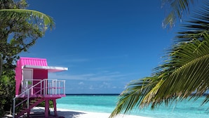 A pink lifeguard tower on a white sandy beach with clear turquoise water and palm trees. -  Ifuru Island Maldives  (Ifuru)