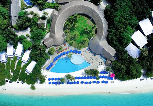 An aerial view of a resort with a central pool, multiple beachside umbrellas, and a circular building structure. -  Ifuru Island Maldives  (Ifuru)