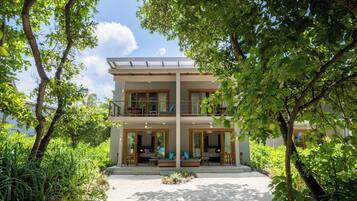 A two-story building with a covered balcony, surrounded by lush greenery.