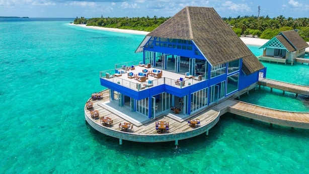 A blue overwater bungalow with a thatched roof, surrounded by turquoise waters and a white sandy beach. -  Ifuru Island Maldives  (Ifuru)