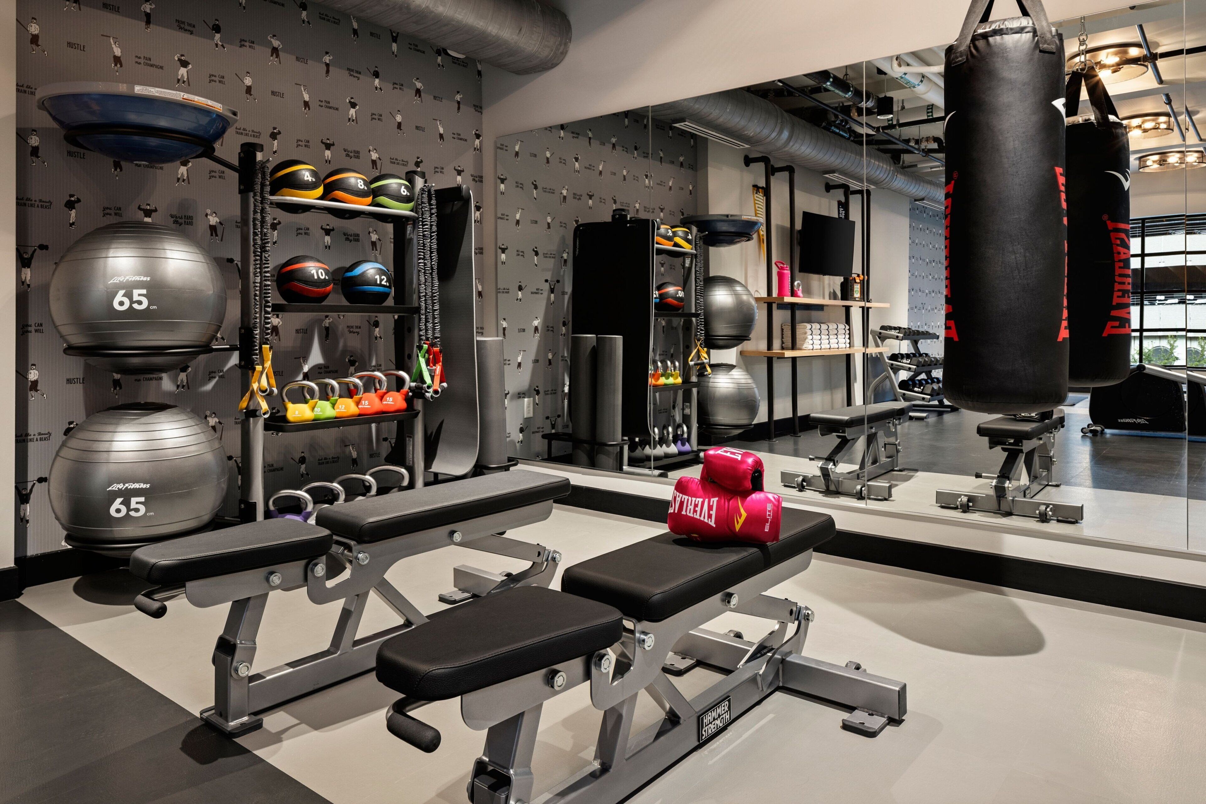 Un gimnasio con equipo de levantamiento de pesas, una banca y guantes de boxeo.