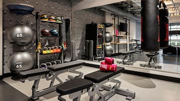 Un gimnasio con equipo de levantamiento de pesas, una banca y guantes de boxeo.