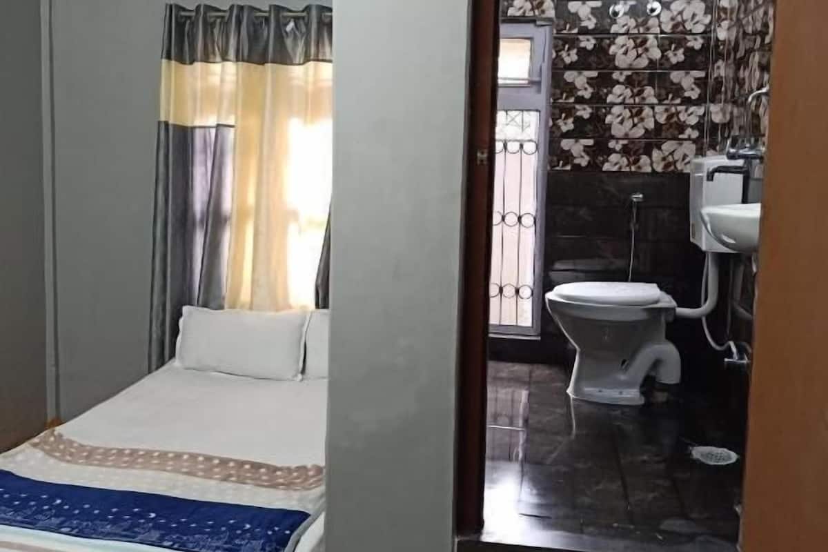 Ein Schlafzimmer mit Bett, Deckenventilator und Blick ins Bad mit Toilette und Waschbecken.