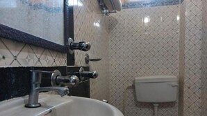 Un baño con lavamanos blanco, espejo e inodoro.