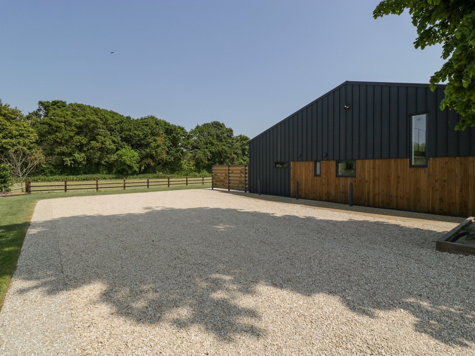 A modern building with a gravel driveway and a wooden fence.