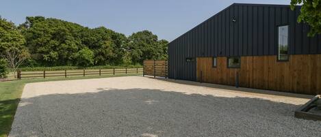 A modern building with a gravel driveway and a wooden fence.