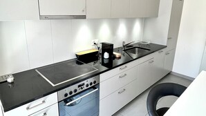 Una cocina moderna con encimera negra, electrodomésticos de acero inoxidable y armarios blancos.