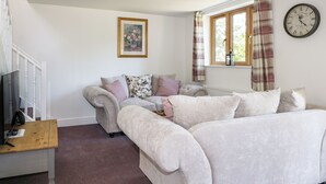 A living room with a beige sofa, a wooden coffee table, and a television on a stand. - Foxes Earth (Salisbury)