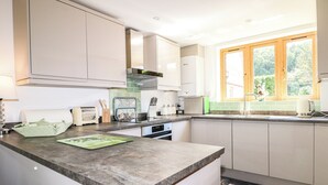 A modern kitchen with a granite countertop, white cabinetry, and a window providing natural light. - Foxes Earth (Salisbury)
