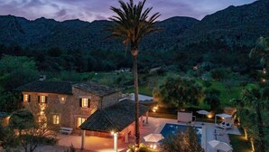 A stone building with multiple rooms, a pool area with umbrellas, and a palm tree. - Villa Sa Mola, a splendid majorcan house located in a privileged enclave. (Cala San Vicente)