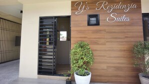 Entrada de um edifício com uma placa que diz 'Y's Residencia Suites'.