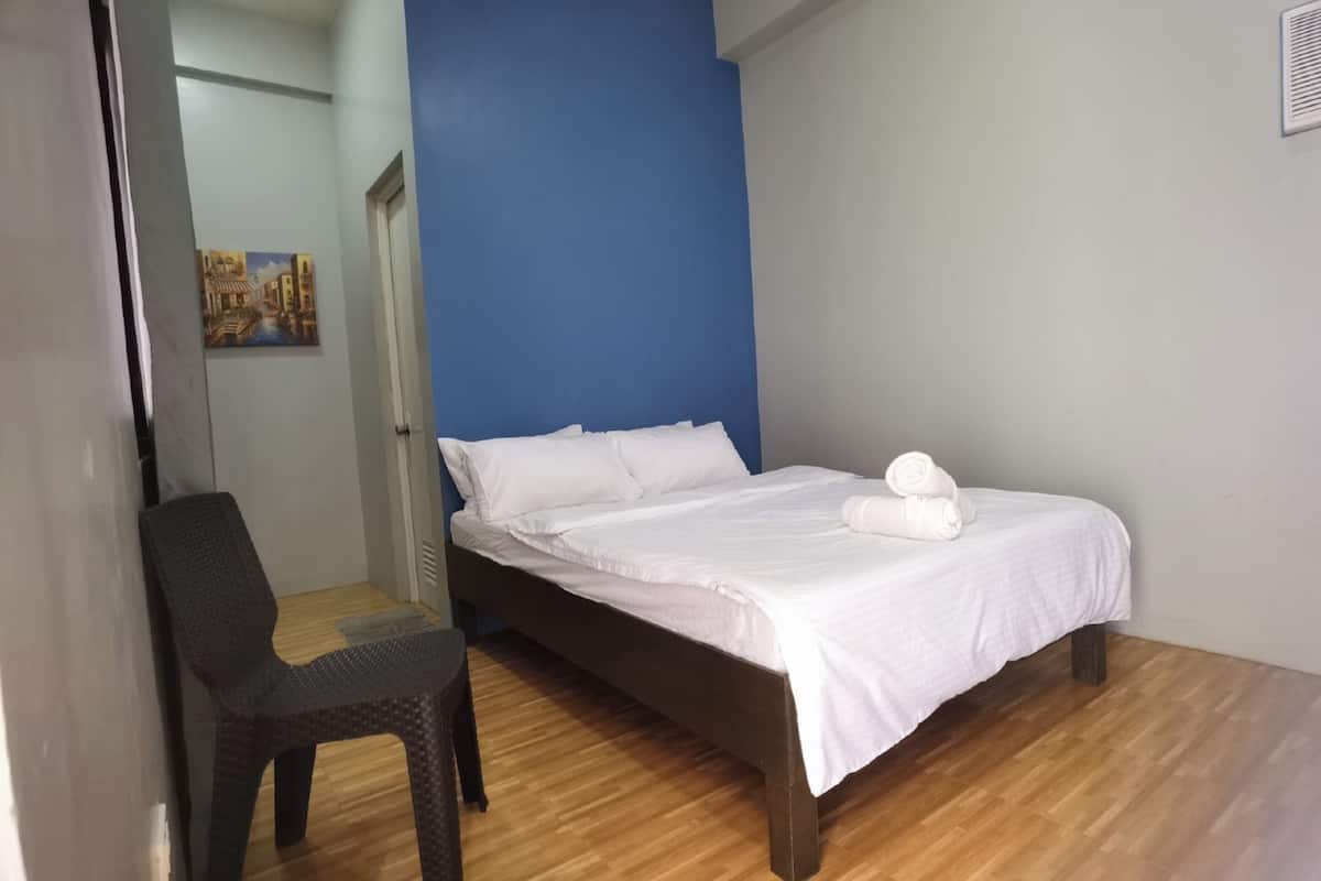 Ein Schlafzimmer mit einem Bett, einem Sessel und einem Bild an der Wand.