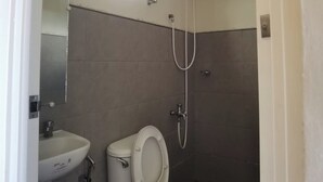 Uma casa de banho pequena com sanita, lavatório e chuveiro.