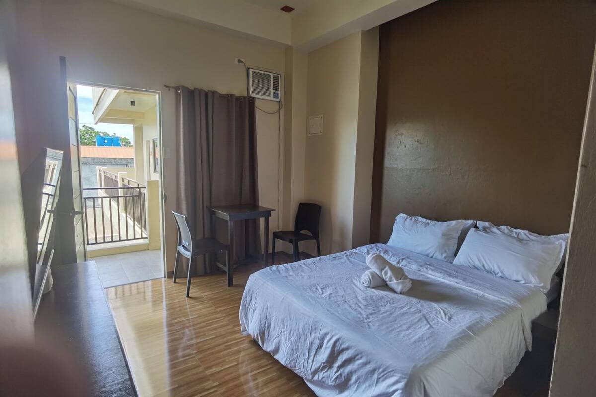 Ein Hotelzimmer mit Bett, Schreibtisch, Stuhl und Balkon.