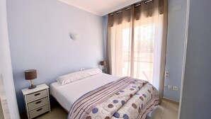 Una camera da letto con un letto, un comodino, una lampada e una finestra con tende.