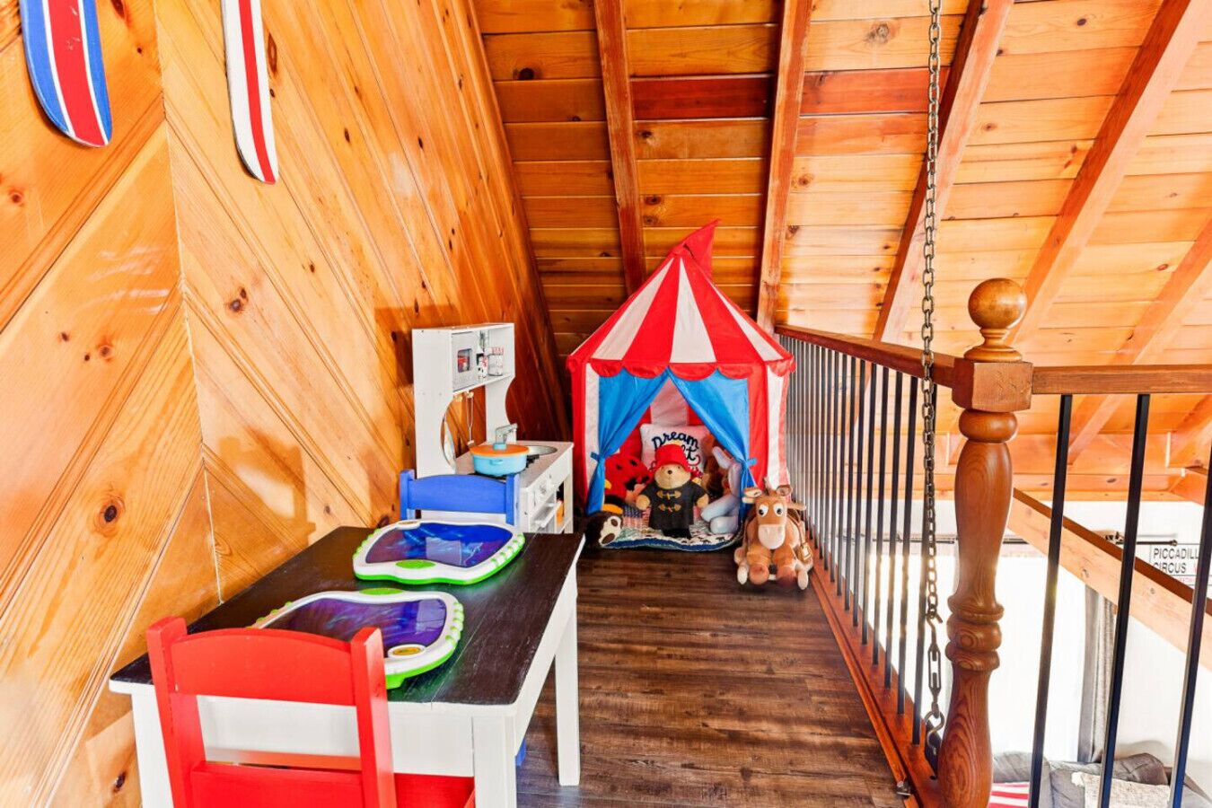 L’intérieur d’un chalet en bois, avec une table à manger, des chaises, une petite tente de jeu et un cheval en jouet.