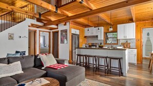 A spacious living area with a sofa, coffee table, and a kitchen with a central island and stools. - Pet Friendly With A Hot Tub In Big Bear Lake (Big Bear Lake)