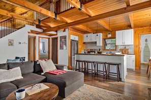 A spacious living area with a sofa, coffee table, and a kitchen with a central island and stools.