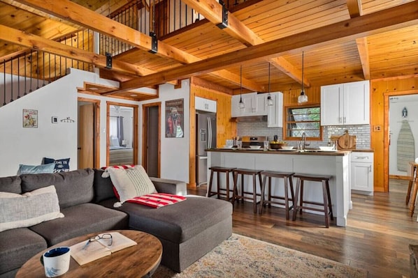 A spacious living area with a sofa, coffee table, and a kitchen with a central island and stools.
