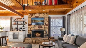 A cozy living room with a stone fireplace, a television mounted above it, and a comfortable seating area with a sofa and armchairs. - Pet Friendly With A Hot Tub In Big Bear Lake (Big Bear Lake)