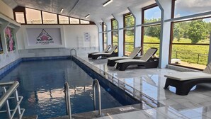 Une piscine avec des chaises longues et une vue sur l’extérieur.