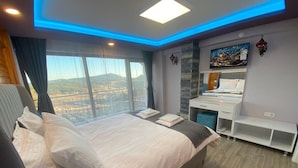 Une chambre d’hôtel moderne avec un grand lit, un bureau et une vue sur les montagnes.