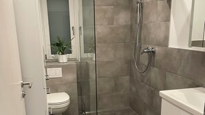 A modern bathroom with a glass shower enclosure, a toilet, and a sink. - Quiet accommodation with best location for trips to Nuremberg and surroundings  (Feucht)
