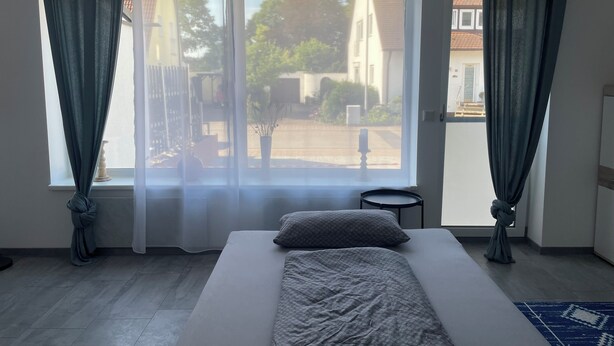 A bedroom with a bed, a small table, and a view of the outside. - Quiet accommodation with best location for trips to Nuremberg and surroundings  (Feucht)