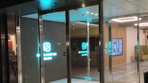 A modern building entrance with glass doors, a digital display, and a seating area inside. - Prince Smart Inn Miyazaki (Miyazaki)
