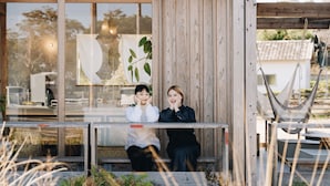 Two people sitting on a wooden bench outside a building with a large window. - Prince Smart Inn Miyazaki (Miyazaki)