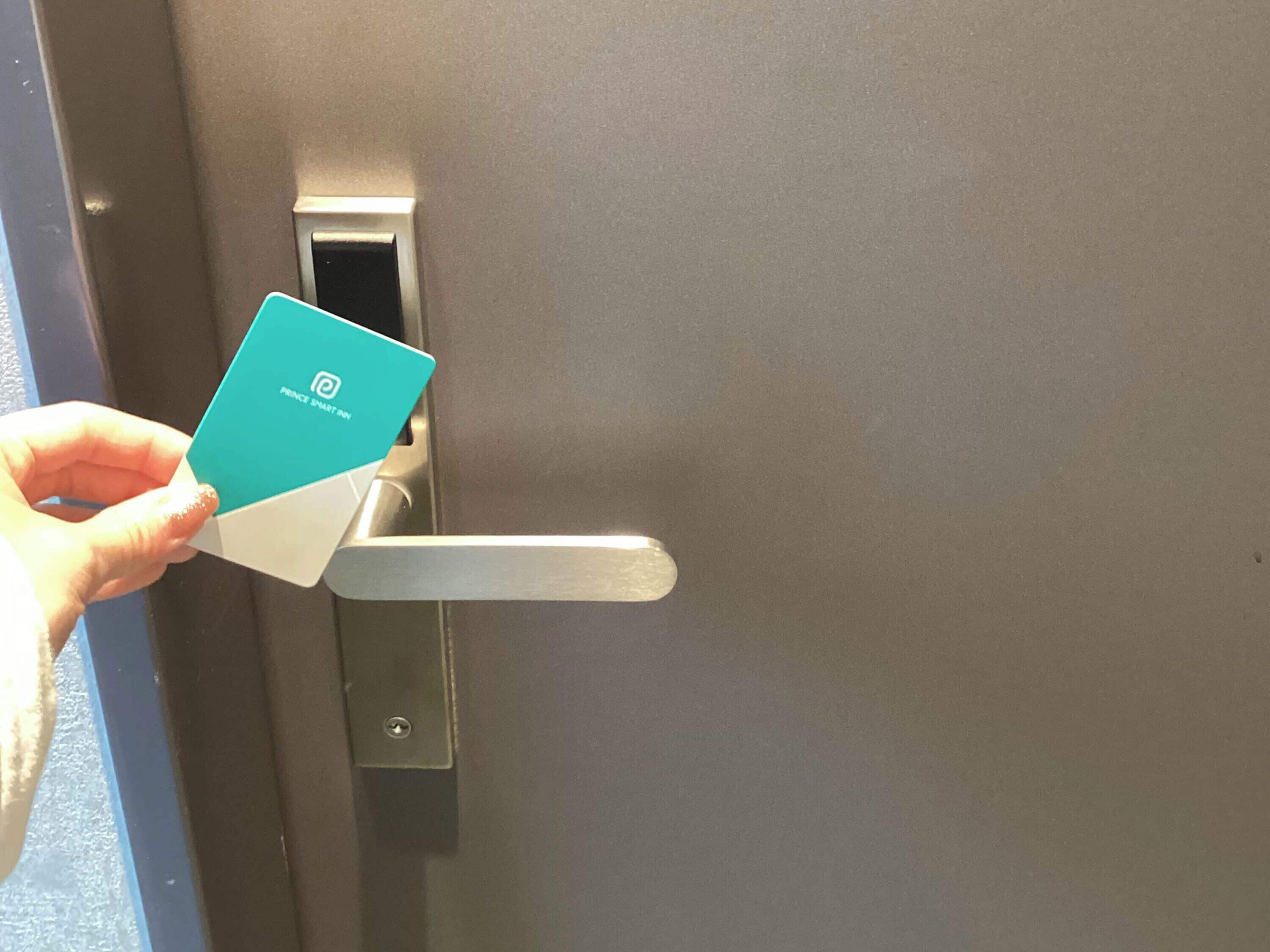 Una mano sosteniendo una tarjeta azul con un logotipo, introduciéndola en la cerradura metálica.