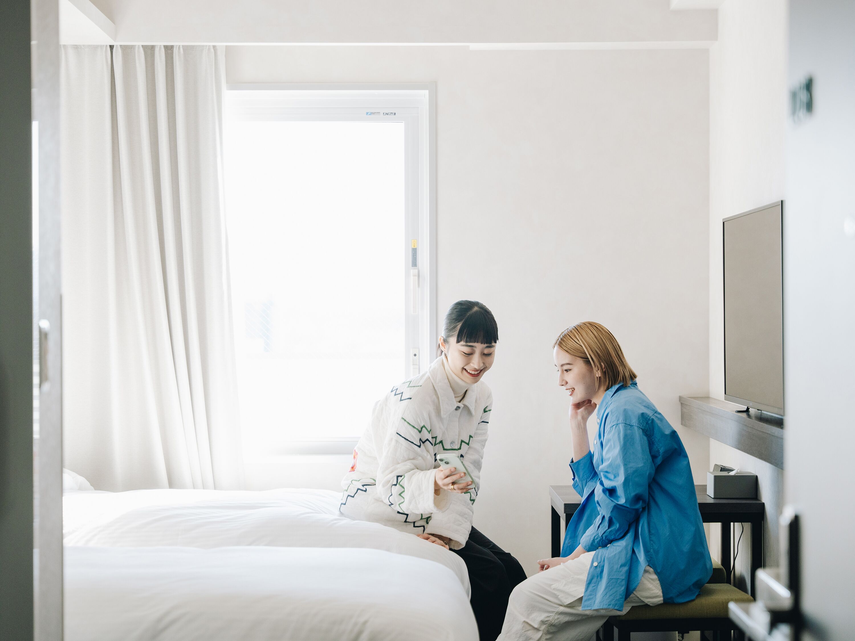 Ein Hotelzimmer mit einem Bett, einem Fernseher und einem Fenster mit Vorhängen.