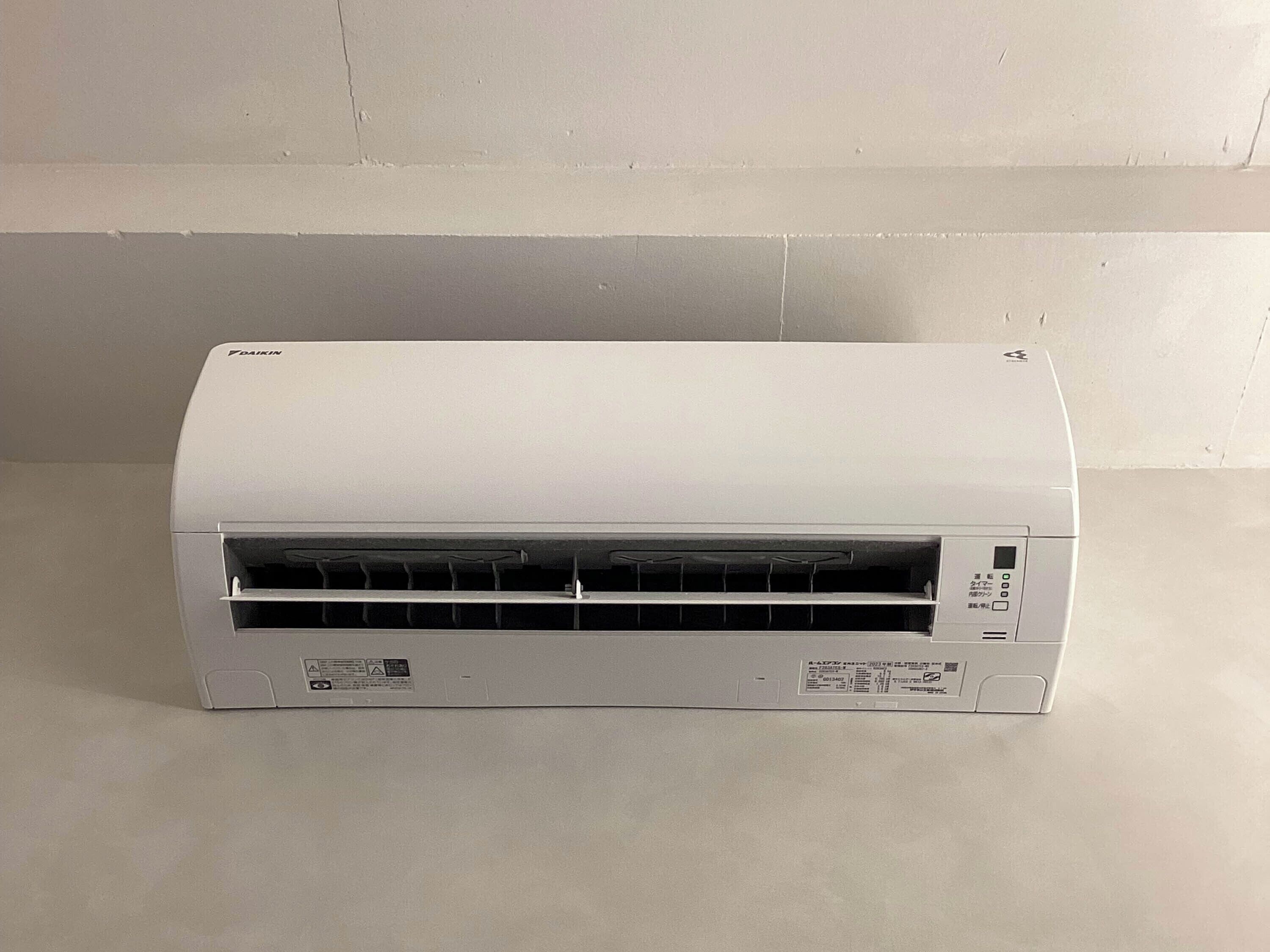 A Daikin air conditioner unit with a control panel, vent, and a label on the bottom.