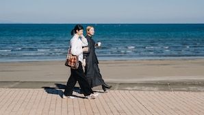 Two people walking on a paved path by the beach, with the ocean in the background. - Prince Smart Inn Miyazaki (Miyazaki)