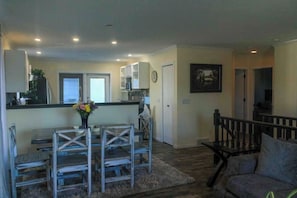 A spacious living area with a dining table, chairs, a sofa, and a staircase.