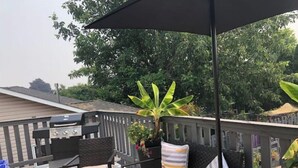 Una terraza con mobiliario exterior, una parrilla y una planta en maceta.