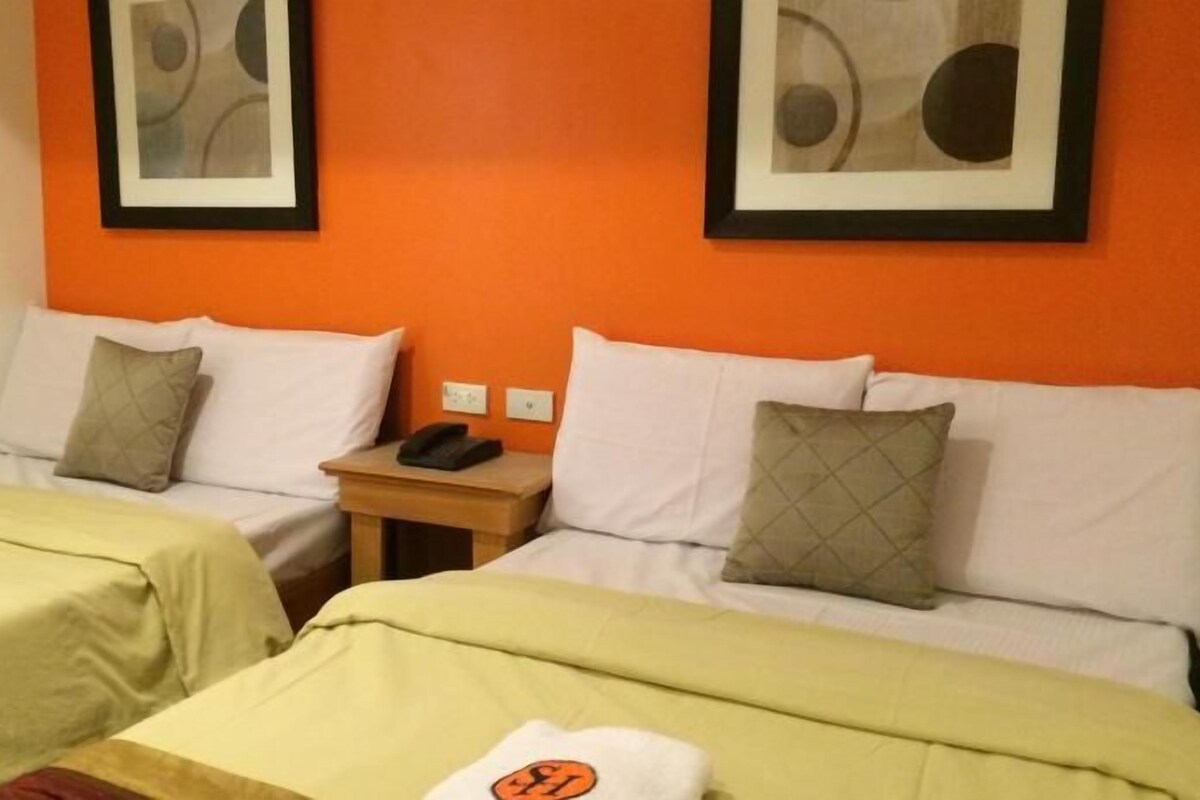 A hotel room with two beds, a nightstand, and a telephone.