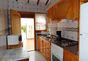 Una cocina con armarios de madera, estufa, pileta y microondas.