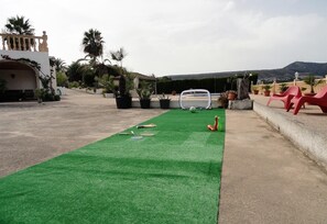 A rooftop with a green artificial turf area, a soccer goal, and red plastic chairs.