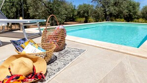 Un espace aménagé au bord de la piscine, avec un panier en osier, un chapeau de paille et un tapis à motifs.