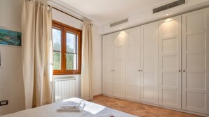 Une chambre à coucher avec un lit, un radiateur, une fenêtre avec des rideaux et une armoire.